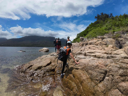 Kids on a rocky shoreline with mountains and trees in the background